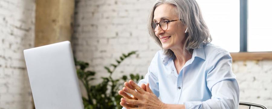 Woman with headphones smiling at computer