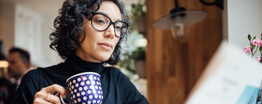  Businesswoman drinking coffee and reading a newspaper.