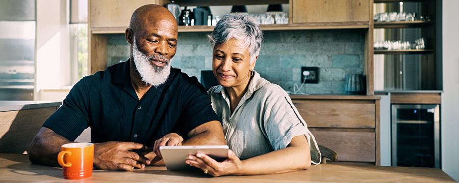 Couple looking at Ipad at kitchen table.