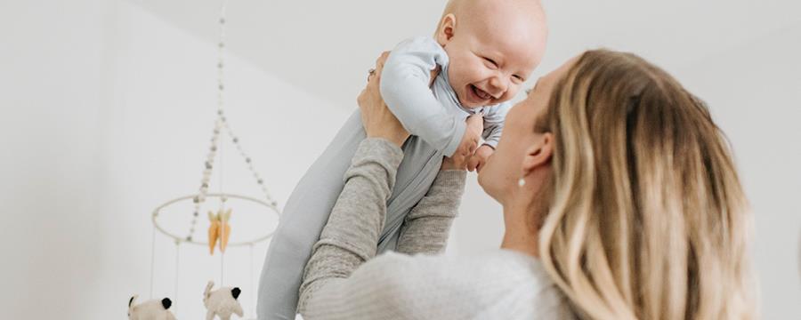 Mother holding up laughing baby