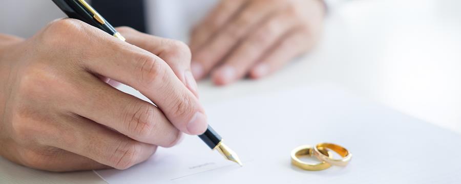 Hand signing document with rings on paper