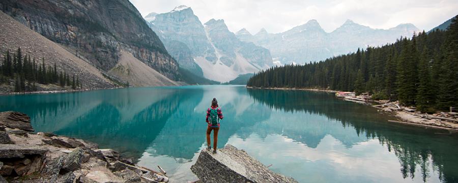 Hiker enjoying the views of a mountain range and lake.
