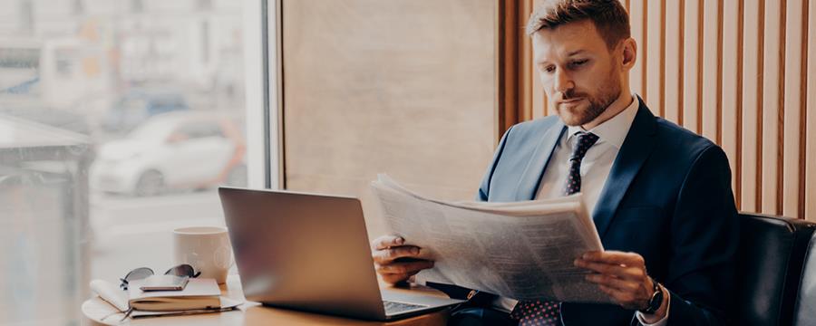 Young businessman reading newspaper at coffee shop.