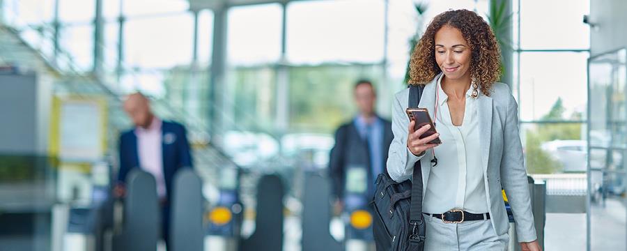 Businesswoman in the airport, looking at smartphone.