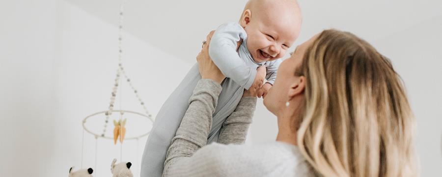 A mom holding a giggling baby.