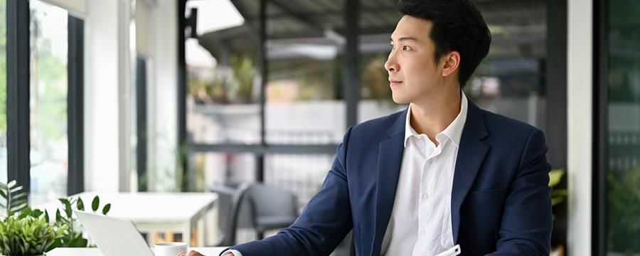 Businessman at his office desk looking out the window with a thoughtful expression