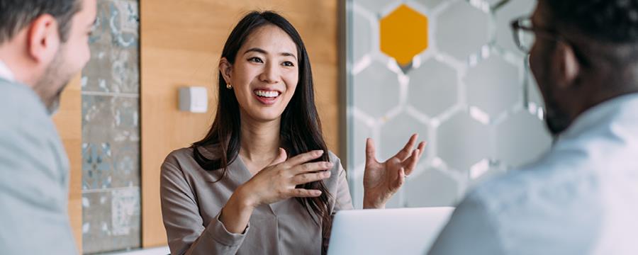 Woman talking animatedly with her two work colleagues in a light, airy office