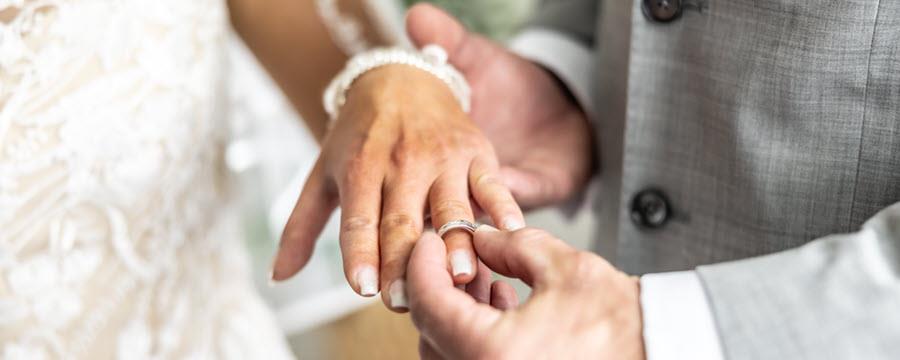 Groom putting wedding band on bride.
