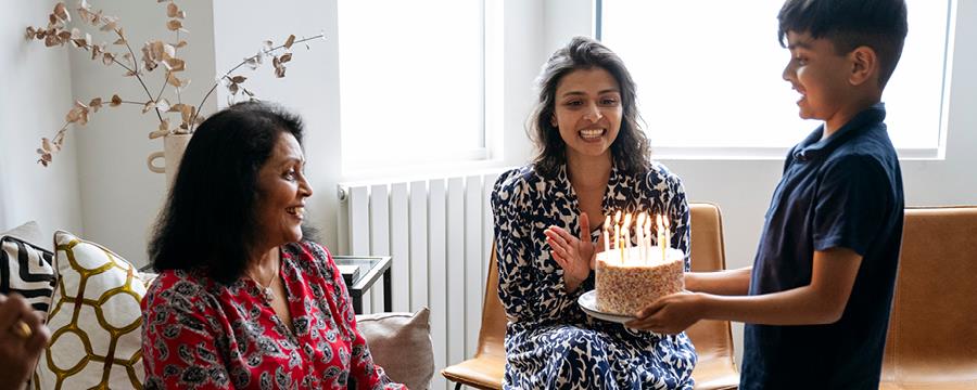 Young boy blowing out candles on birthday cake.