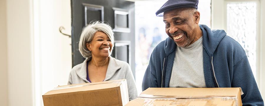 Retired couple carrying boxes into their new home.