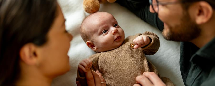 A mother and father looking fondly at their newborn baby.