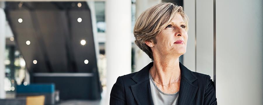 Businesswoman cheerfully looks out of the window at her place of work.
