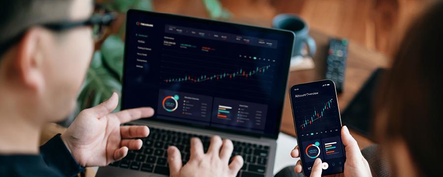 Couple looking at investment performance on a laptop and smartphone