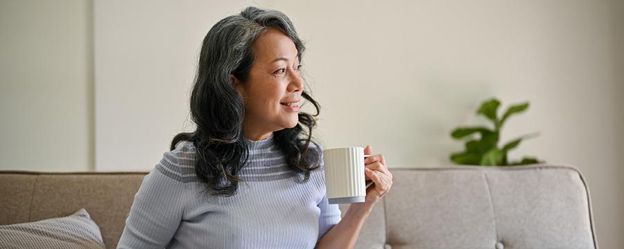 Happy woman drinking coffee, looking out window.