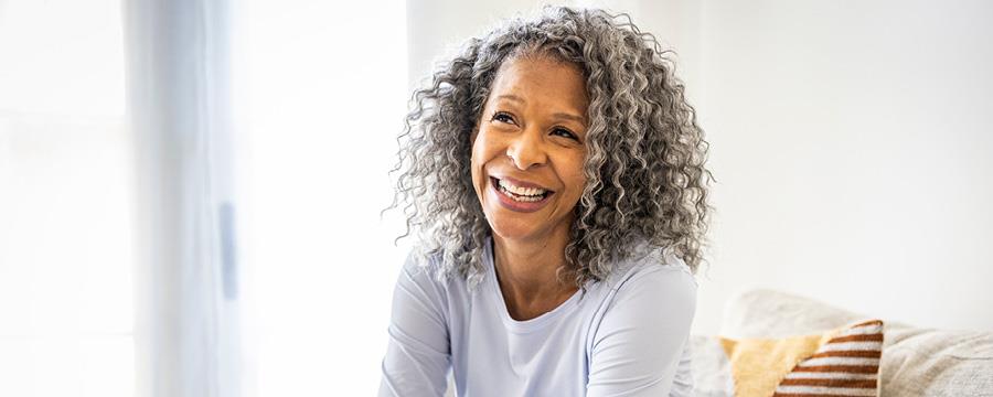 Woman sitting at home on couch, smiling