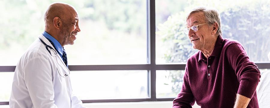 Senior man talking with doctor in exam room