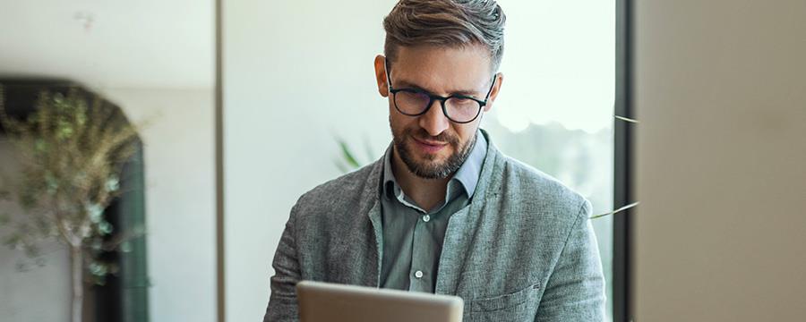 Businessman in office drinking coffee and looking at tablet.