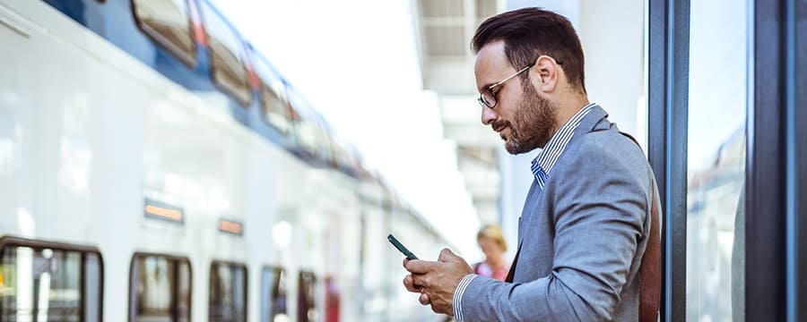 Businessman looking at his phone while waiting for the train