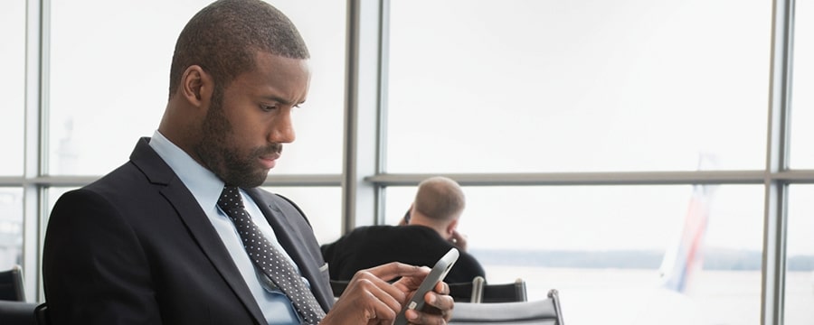 Businessman looking at smartphone at airport.