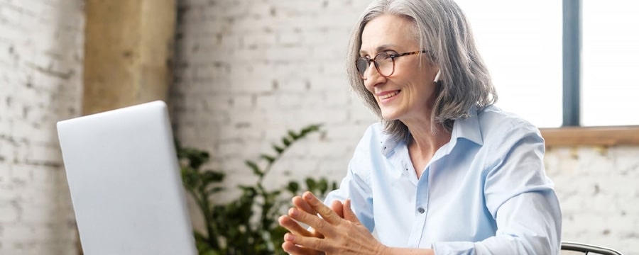 Woman with headphones smiling at computer