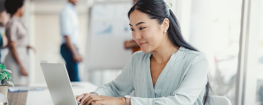 Woman in an office typing on a laptop