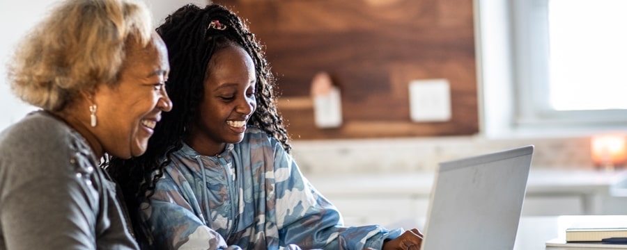 Grandmother and granddaughter smiling at laptop